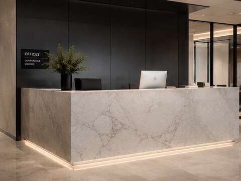 Office reception desk in light quartzite with a backlit base against a dark accent wall