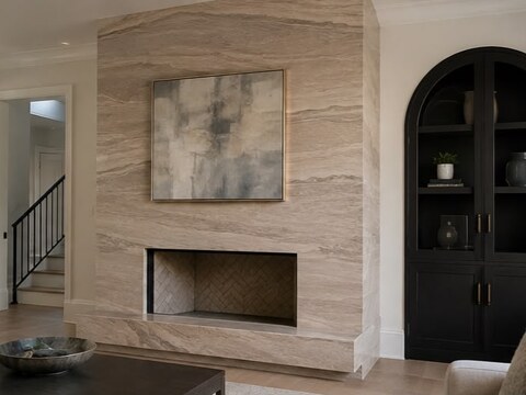 Floor-to-ceiling travertine slab fireplace wall beside an arched black built-in cabinet