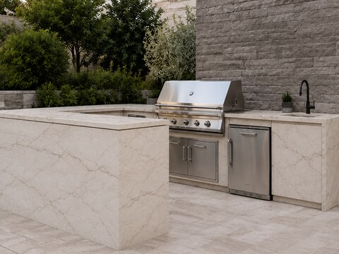 Outdoor kitchen with waterfall-edge quartz island, built-in grill, and stacked stone accent wall